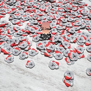 May include: A large quantity of gray and red koala bear charms with Santa hats. The charms are scattered on a white wooden surface.