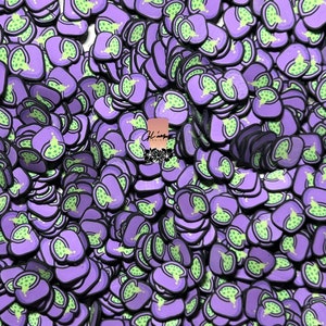 May include: A large quantity of purple and green  pepper slice shaped resin charms. The charms are flat and have a black outline.