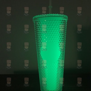 May include: A clear, green, glow-in-the-dark reusable tumbler with a textured diamond pattern and a straw.