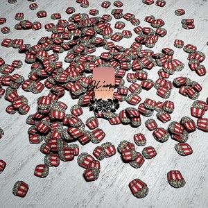 May include: A large quantity of red and white popcorn bucket charms. The charms are scattered on a white surface.