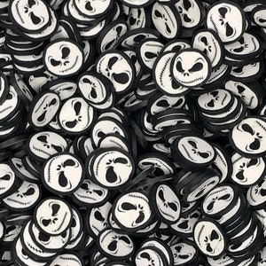 May include: A large pile of black and white round stickers with a cartoon face on them. The face is white with black eyes and a stitched mouth.