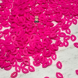 May include: A large pile of hot pink plastic lips, scattered on a white surface. The lips are all the same size and shape, and they are arranged in a random pattern.