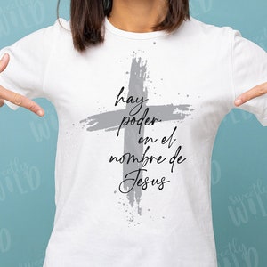 May include: A white t-shirt with a gray cross and the text "hay poder en el nombre de Jesus" printed on the front.