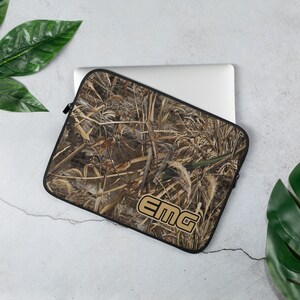 May include: A brown and tan camouflage laptop sleeve with a black zipper and the text "EMG" in gold letters.
