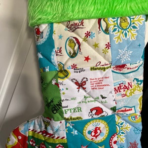May include: A green and white Christmas stocking with a patchwork design featuring the Grinch. The stocking has a green fur cuff and includes text such as "Grinch", "Where's my gift?", "Merry", "You all on my naughty list", "Grinchmas", and "You're a Mean One, Mr. Grinch".