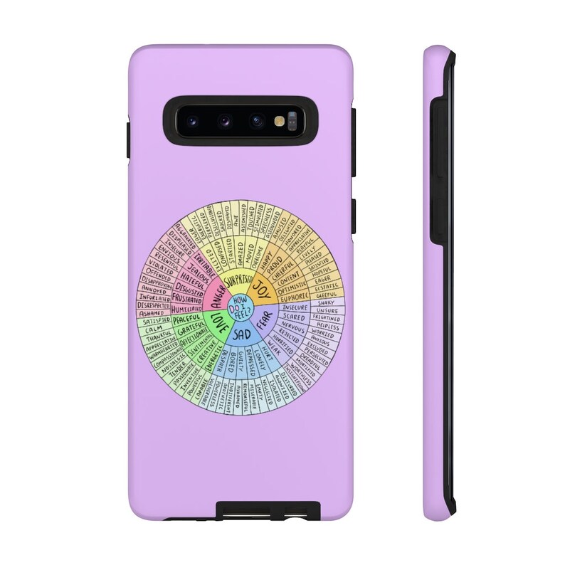 May include: A lavender phone case featuring a colorful emotion wheel design. The wheel is divided into sections with words like "joy," "sad," and "fear." The case has a black border and a camera cutout.