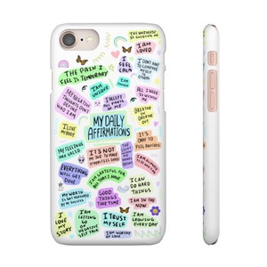 May include: A white phone case with colorful text and illustrations. The text includes positive affirmations such as "I am loved", "I am unique", "My daily affirmations", "I am grateful for all that I have", "I trust myself", and "I am worthy of love".