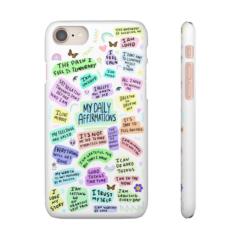 May include: A white phone case with colorful text and illustrations. The text includes positive affirmations such as "I am loved", "I am unique", "My daily affirmations", "I am grateful for all that I have", "I trust myself", and "I am worthy of love".