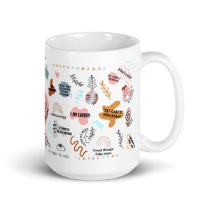 Puede incluir: Taza de cer&aacute;mica blanca con un dise&ntilde;o envolvente con frases inspiradoras e ilustraciones coloridas. La taza incluye frases como "Soy suficiente" y "El autocuidado es importante".