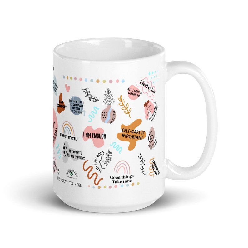 Puede incluir: Taza de cer&aacute;mica blanca con un dise&ntilde;o envolvente con frases inspiradoras e ilustraciones coloridas. La taza incluye frases como "Soy suficiente" y "El autocuidado es importante".