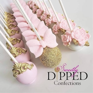 Puede incluir: Cake pops rosas y dorados decorados con lazos, flores y detalles dorados. Los cake pops están en palitos y dispuestos en fila. La imagen incluye el texto "Sweetly Dipped Confections".