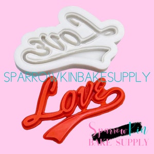 May include: A white silicone mold and a red silicone mold, both shaped like the word "Love" in a cursive font. The molds are used for baking and decorating cakes and other desserts.
