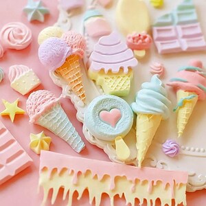Puede incluir: Una colecci&oacute;n de mini conos de helado, cupcakes y caramelos de color pastel. Los conos de helado est&aacute;n decorados con chispas y virutas de chocolate. Los cupcakes est&aacute;n cubiertos con glaseado y chispas. Los caramelos tienen forma de corazones y estrellas.