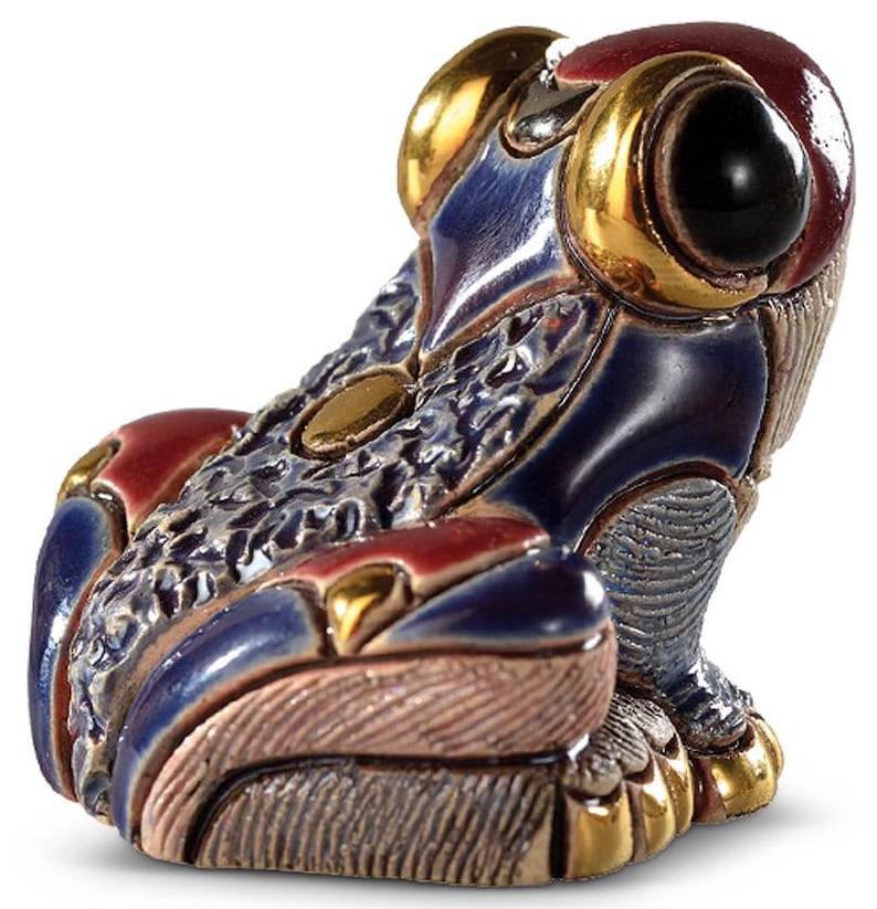 May include: A small, blue and gold ceramic frog figurine with intricate details. The frog has a textured surface and a large, black eye.