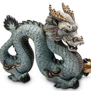 May include: A blue and gold ceramic dragon figurine with intricate details. The dragon is curled up with its tail wrapped around its body and holding a golden orb in its claws.