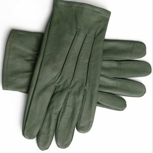 May include: A pair of green leather gloves. The gloves are folded in half, with the fingertips of one glove extending beyond the other.