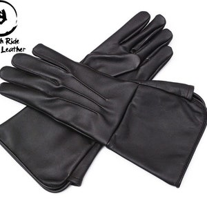 Pode incluir: Um par de luvas de couro preto com punho longo. As luvas são feitas de couro genuíno liso e têm um design simples e elegante.