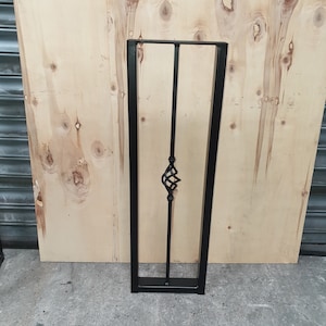 May include: Black metal table leg with a decorative scroll design. The leg is rectangular in shape and has a square base.