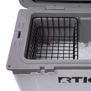 May include: Open view of a gray and white cooler with a black wire basket inside. The cooler is filled with ice cubes. The RTIC logo is visible on the front of the cooler.