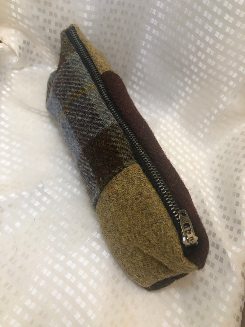 May include: A brown, green and blue patchwork zipped pouch. The pouch is made of a soft, textured fabric.