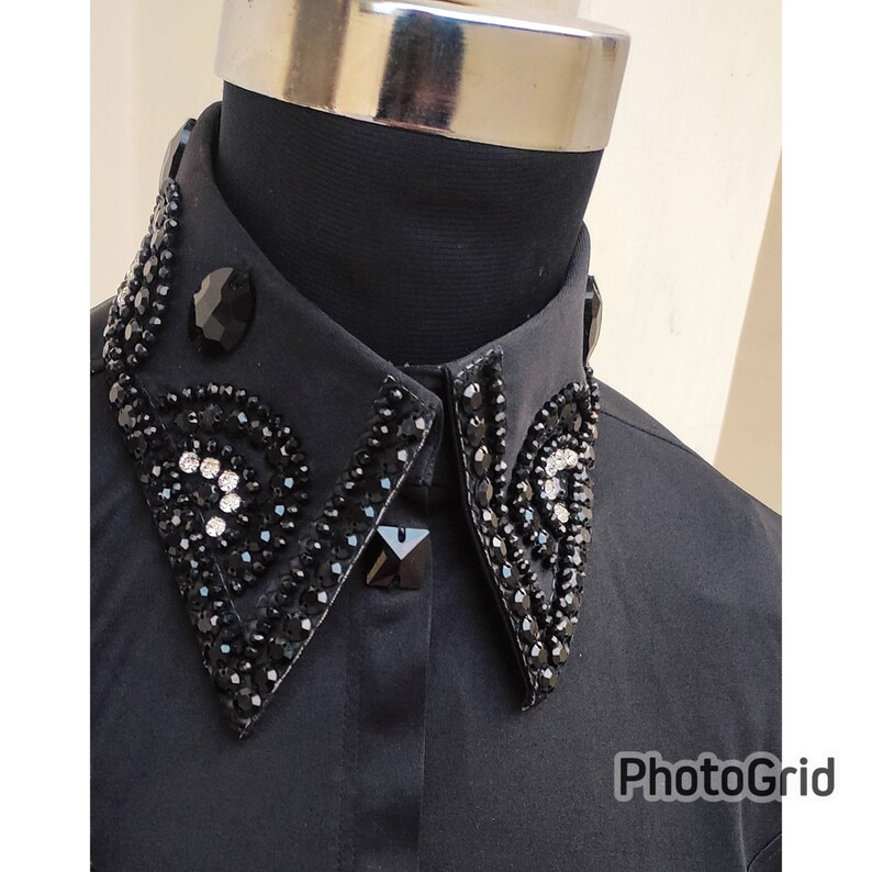 Puede incluir: Una camisa negra con un cuello grande adornado. El cuello est&aacute; decorado con diamantes de imitaci&oacute;n negros y transparentes en un patr&oacute;n geom&eacute;trico.