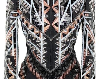 May include: A black show jacket with a geometric pattern in white, silver, and copper. The jacket has a zipper closure and long sleeves. The sleeves and front of the jacket are embellished with fringe.