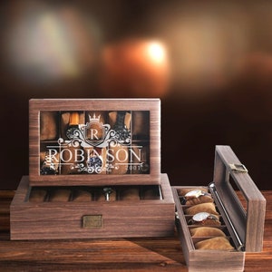 May include: A wooden watch box with a glass top and a personalized inscription that reads "R ROBINSON 2001". The box has a brown finish and is open to reveal a velvet interior with slots for watches.