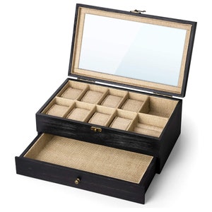 May include: Black wooden watch box with a glass top and a drawer. The box has nine compartments for watches and a lined interior.