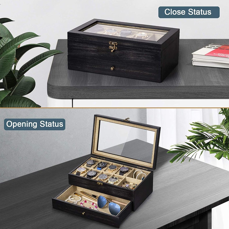 May include: A black wooden watch box with a glass top and a drawer. The box is open and has multiple watch compartments. The drawer is open and contains sunglasses, a necklace, and a pen.