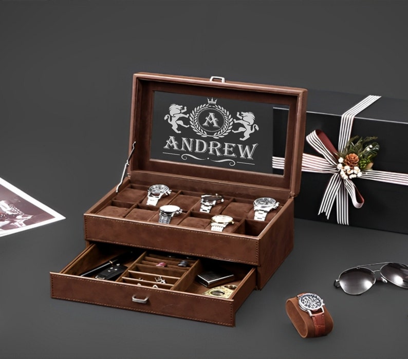 May include: A brown leather watch box with a glass top. The box has a drawer and is engraved with the name "Andrew" and a crown. The box is open and has several watches inside.