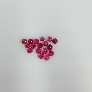 以下が含まれることがあります： 赤とピンクの色合いが異なる、小さくて丸い研磨された宝石のコレクション。 宝石は白い表面に散らばっており、滑らかで反射する表面が際立っています。 ジュエリー作りに使用できます。