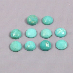 May include: Ten round, turquoise gemstones with faceted surfaces are displayed on a grey background. The stones vary in colour and texture, with some showing natural veining. These gemstones are suitable for jewellery making.