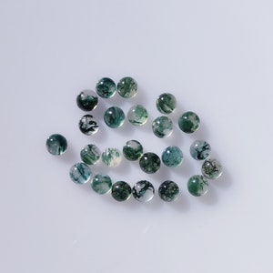 May include: A collection of round, polished moss agate gemstones. The translucent stones display a mix of green, white, and clear inclusions, creating a natural, organic pattern. These gemstones are ideal for jewelry making or collecting.