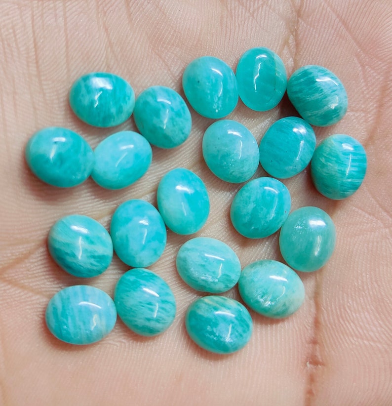 Pu&ograve; includere: Una collezione di pietre preziose di amazzonite ovali in varie tonalit&agrave; di turchese e verde-blu. Le pietre lucide presentano motivi unici, perfette per la creazione di gioielli o il collezionismo. Ogni pietra misura circa 1-2 cm.