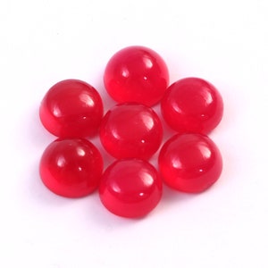 Peut inclure: Sept pierres pr&eacute;cieuses rondes, polies, d'un rouge vif, sont dispos&eacute;es sur un fond blanc. Les pierres en cabochon ont une surface lisse et brillante, refl&eacute;tant la lumi&egrave;re. Ces pierres conviennent &agrave; la fabrication de bijoux ou &agrave; l'artisanat.