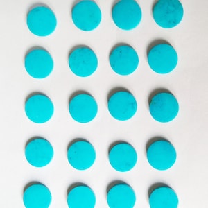 May include: Twenty round, polished turquoise gemstones, each with a vibrant, solid blue-green color. The stones are arranged in a grid pattern against a white background, showcasing their natural beauty and potential for jewelry making or crafting.