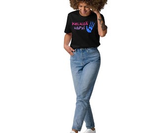 May include: Black t-shirt with the text "KELKUA HARXI" in pink and blue, and a blue handprint. The person is wearing light blue jeans and white sneakers.