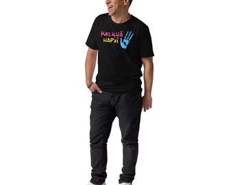 May include: Black t-shirt with the text "KELKÜÄ HAPXİ" in pink and yellow, and a blue handprint graphic. The person is wearing black jeans and white sneakers.