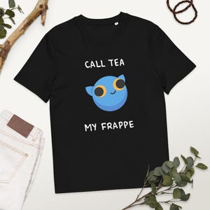 以下が含まれることがあります： 「CALL TEA MY FRAPPE」の文字と、大きな黄色の目を持つ青い漫画のキャラクターが描かれた黒いTシャツ。柔らかい素材で作られており、クルーネックです。
