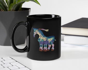 May include: A black ceramic mug featuring a colorful graphic illustration of a six-legged creature with blue, purple, and cream-colored patterns. The creature has a long neck, a crest on its head, and brown hooves, centered on the mug's side.