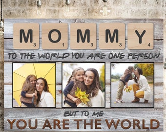 May include: A wood sign with the word "MOMMY" spelled out in Scrabble tiles. The sign says "To the world you are one person, but to me you are the world". The sign has three photos of a mother and her children.