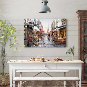 May include: A painting of a Parisian street scene with the Eiffel Tower in the background. The street is cobblestone and there are shops and cafes on either side. People are walking and sitting at tables outside the cafes. The painting is in a realistic style and has a warm, inviting feel.