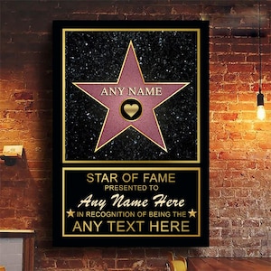 Op de afbeelding: Een roze ster met een gouden rand op een zwarte achtergrond met gouden glitter. De ster heeft een gouden hart in het midden en de tekst "ANY NAME" erop. Onder de ster bevindt zich een gouden plaquette met de tekst "STAR OF FAME PRESENTED TO Any Name Here IN RECOGNITION OF BEING THE ANY TEXT HERE".