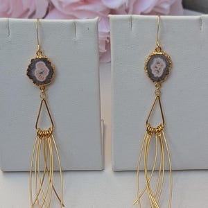 May include: Gold earrings with a pink and gray agate stone pendant and a long, thin gold chain with multiple strands.