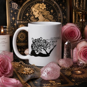 Puede incluir: Una taza de cerámica blanca con un gráfico negro de una figura reclinada con cabello en espiral, junto con el texto "VIRGO" y "I AM A PRACTICAL BITCH WHO CORRECTS THE SLOPPY & LAZY" impreso en negro en el lateral.