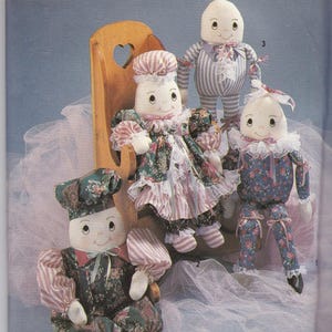 Op de afbeelding: Simplicity Crafts patroon met verschillende handgemaakte stoffen poppen. De poppen hebben geschilderde gezichten en zijn gekleed in verschillende outfits, waaronder bloemenjurken, gestreepte pyjama's en een koksuniform. Het patroon is van Faith Van Zanten.