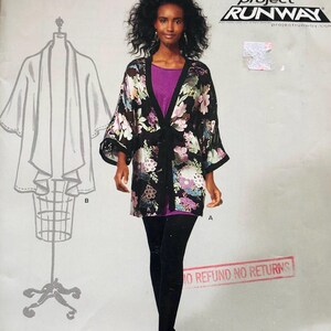 Pode incluir: Um padrão de costura New Look Workroom com um casaco estilo quimono floral. O padrão inclui um desenho do casaco e o texto "FROM Project Runway". A modelo está a usar o casaco sobre um top roxo e leggings pretas.