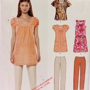 May include: A New Look sewing pattern envelope 6785 featuring illustrations of a peach-coloured tunic with puff sleeves, a floral print sleeveless dress, a patterned top, and two pairs of straight-leg trousers in beige and orange, with text including "NEW LOOK" and "BIN 15".