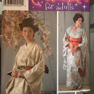 Può includere: Cartamodello Simplicity 4080 per costumi da adulto con kimono e un'ampia fascia obi. La confezione mostra due varianti dell'indumento, una in tessuto floreale color crema e l'altra in stampa floreale azzurro con un obi rosso.