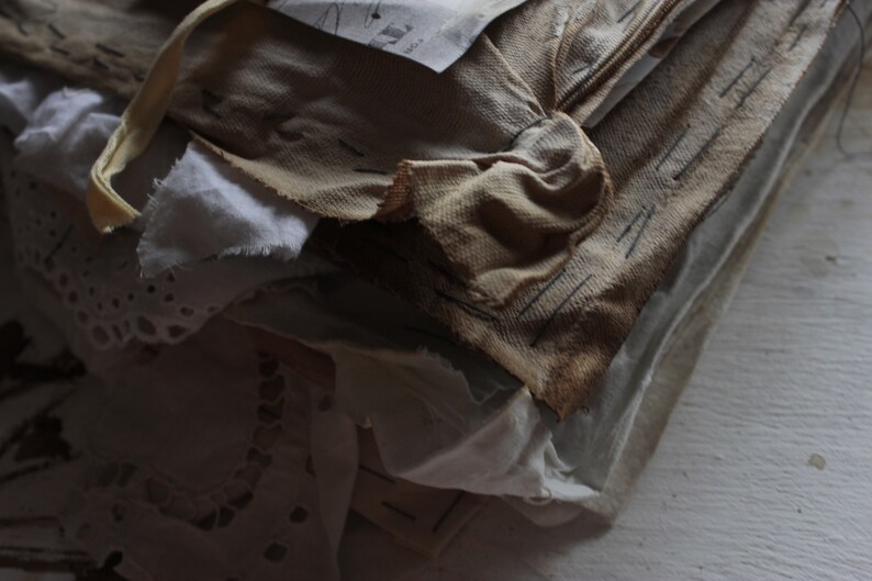 Puede incluir: Una pila de trozos de tela viejos, desgastados y deste&ntilde;idos en tonos de blanco, crema y marr&oacute;n. La tela est&aacute; superpuesta y cosida, creando un aspecto texturizado y r&uacute;stico.